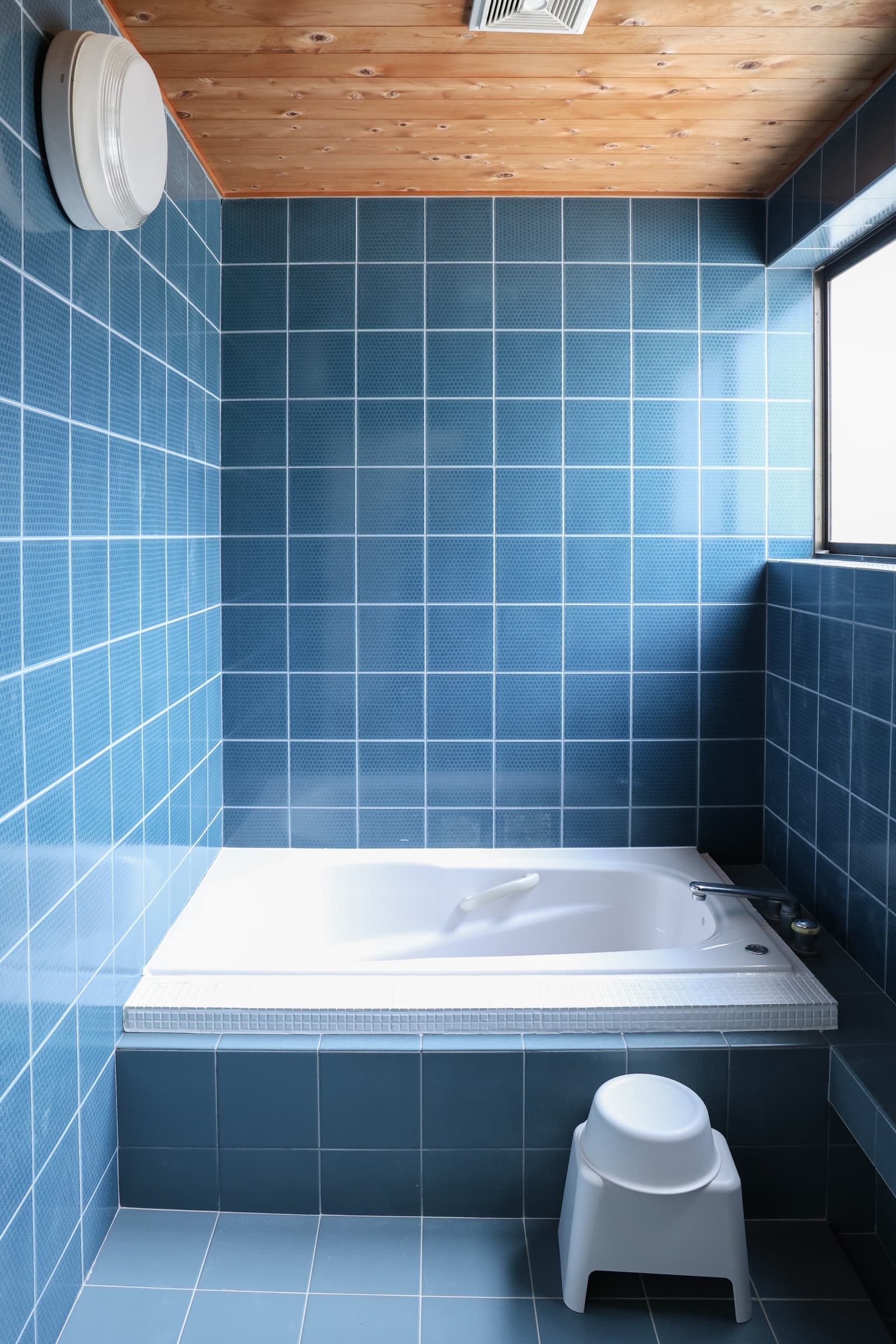 The blue-tiled bathroom with its bathtub