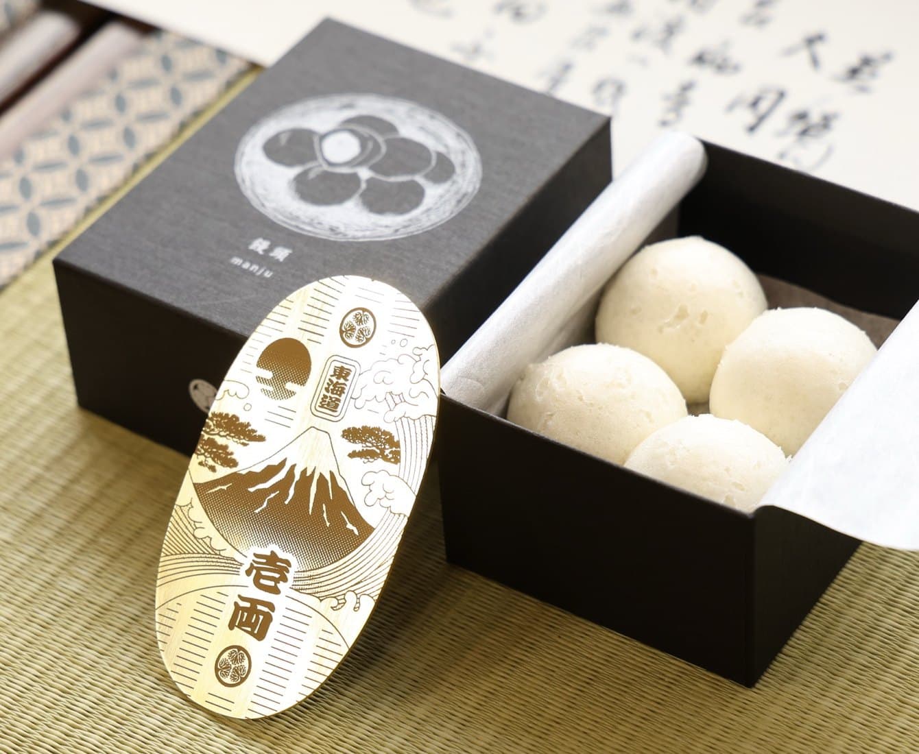 On tatami: a gold koban with Mount Fuji, a box of manju, and a letter written in ink
